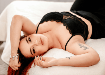 Woman in black lingerie lying on a bed during a boudoir session for a Boudoir Blog.