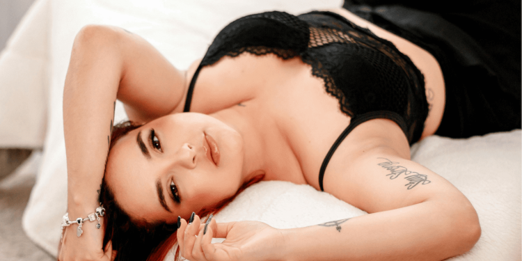 Woman in black lingerie lying on a bed during a boudoir session for a Boudoir Blog.