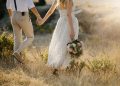 Bride and groom walking hand in hand through a golden field, showcasing romantic Micro Wedding Packages inspiration.