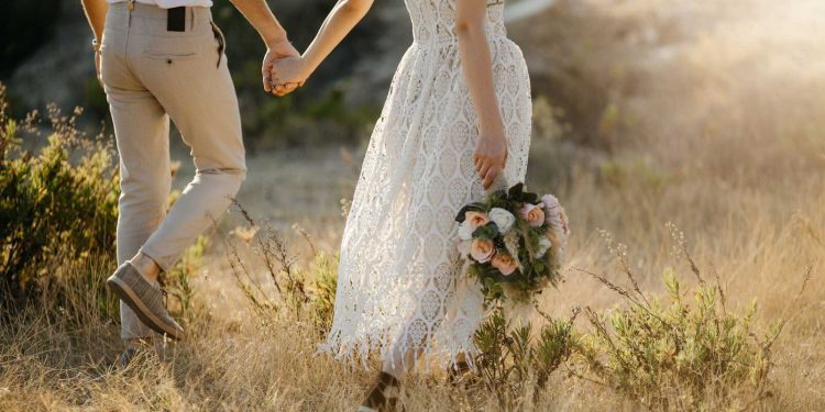 Bride and groom walking hand in hand through a golden field, showcasing romantic Micro Wedding Packages inspiration.