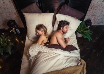 Couple lying back-to-back in bed looking unhappy, illustrating a divorce quiz relationship assessment.