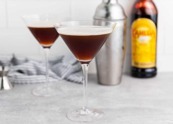 Two Espresso Martini cocktails in martini glasses with cocktail shaker and coffee liqueur.