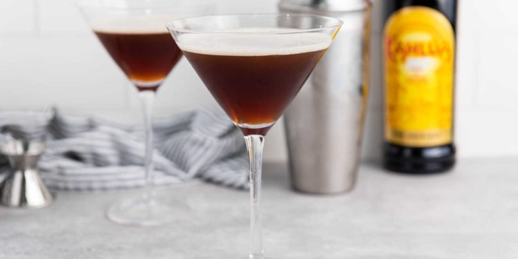 Two Espresso Martini cocktails in martini glasses with cocktail shaker and coffee liqueur.