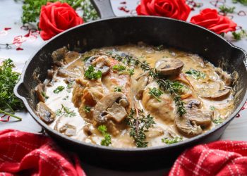 Mushroom White Wine Marry Me Chicken in a skillet with creamy sauce, mushrooms, and fresh herbs, styled with roses.