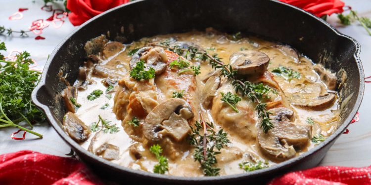 Mushroom White Wine Marry Me Chicken in a skillet with creamy sauce, mushrooms, and fresh herbs, styled with roses.